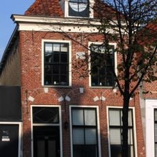 Pand met verdieping, vensternissen en rechte kroonlijst onder zadeldak met dakkapel met ronde fronton