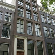 Pand met hoge gevel met deurpartij uit dezelfde tijd, versierde stoep en vier louis