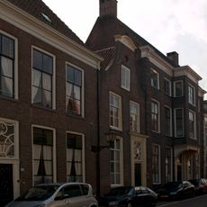 Pand met door gebogen fronton gedekte bakstenen klokgevel met in pilasteromlijsting gevatte voordeur en bovenlicht