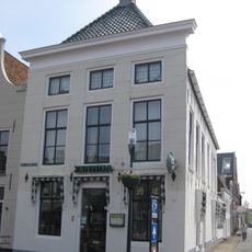 Diep hoekpand met gepleisterde voorgevel met rechte kroonlijst onder schilddak met twee topschoorstenen