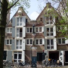 Pakhuis met gave puntgevel waarin tweelichten onder bogen, windkast, toppilaster en op de scheiding met nr 18 waarmee dit pand een groep vormt, een jaartalsteen en een steen met schottenbvrch