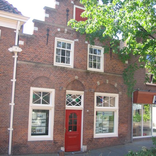 Pand met trapgevel, versierd met geblokte ontlastingsbogen, natuurstenen waterlijsten en sierankers