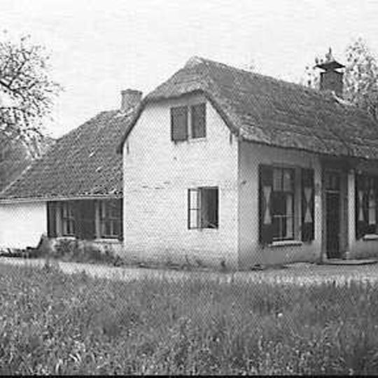 Boerderij, T-huis, klein gedeeltelijk gepleisterd en geheel witgesausd bakstenen gebouw met afgewolfd rieten zadeldak boven het woongedeelte en pannen zadeldak boven het bedrijfsgedeelte