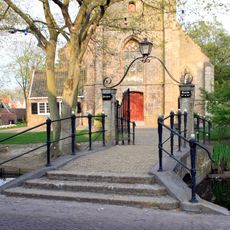 Kerkring. Voor de toren der Hervormde Kerk een boogbrug met balustraden over het water van de Kerkring. Voorts een toegangshek met hardstenen palen
