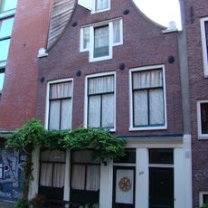 Huis met 19e-eeuws gevel onder klokvormige top met rollagen en gebogen afdekking