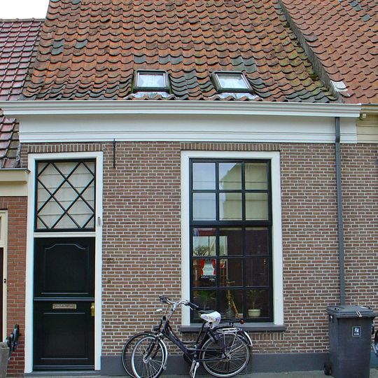 Eenvoudig pand onder zadeldak met deur met bovenlicht en vensters met roedenverdeling, achter gevel met nr. 51