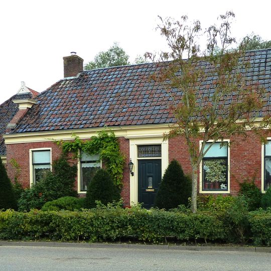 Deels onderkelderd pand met omlijste ingang onder dwars zadeldak met wolfseinden