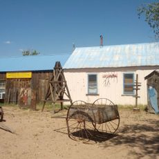 Cut-out mural of Western partiers, cowboy leaning on side of outhouse