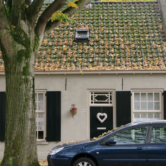 Gepleisterd wevershuisje van begane-grond met pannen zadeldak, dat links aansluit tegen een puntgevel