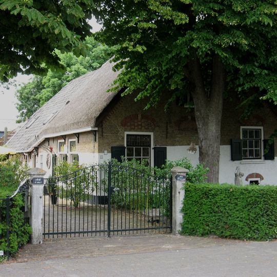 Boerderij "Acht is meer dan duizend". Hoeve, gedateerd in het metselwerk van de voorgevel. Het woongedeelte draagt een rieten wolfdak, is rechts onderkelderd.