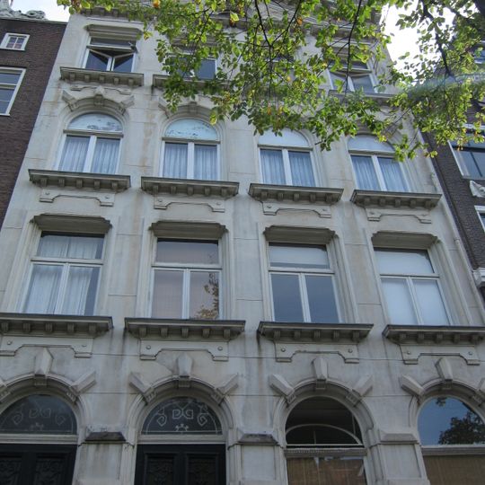 Drie verdiepingen tellend pand onder zadeldak met witgepleisterde gevel, bekroond door een verhoogd, driehoekig doorbroken fronton met tandlijst en obelisk