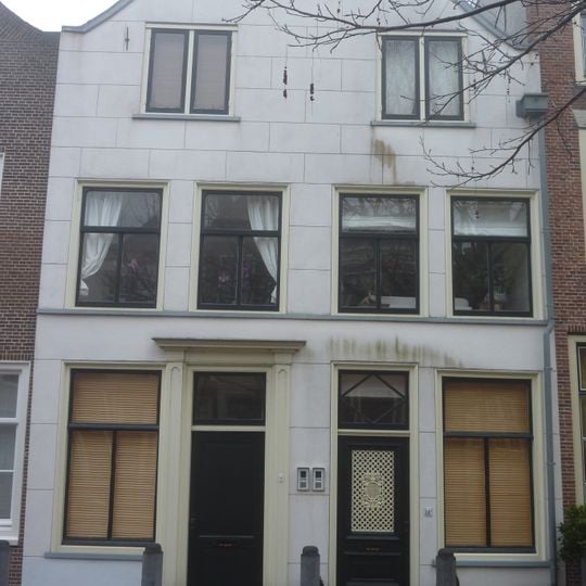 Pand met lage tuitgevel door rechte kroonlijst afgedekt, gepleisterd