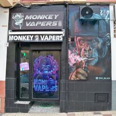 Mural en la fachada de una tienda de cigarrillos electrónicos representando a un chimpancé con gorra fumando un cigarrillo electrónico.