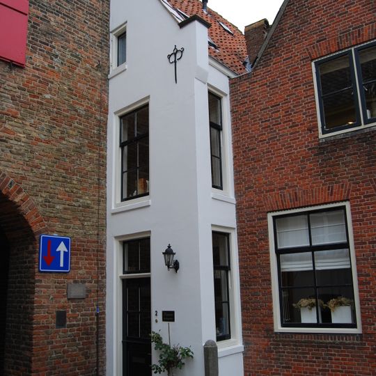 Half puntgeveltje, gepleisterd, tegen de poort