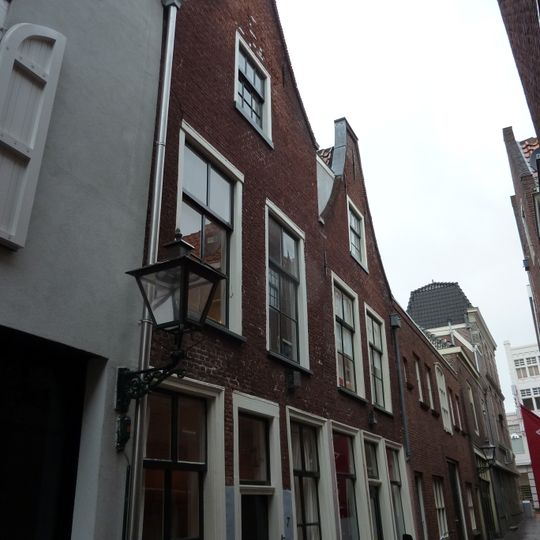 Pand met verdieping onder zadeldak met halsgevel waarin 6-ruitsschuifvensters en geprofileerde omlijstingen; 9-ruitsschuifvenster in top