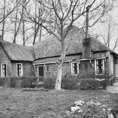 Boerderij onder grotendeels rieten dak met klein voorhuis met zesruitsvensters, ook in het woongedeelte van de schuur