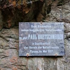 Eine Steinplatte in knapp 2m Höhe an einer senkrechten Felswand, wenige Meter abseits des Pfades im Triebtals.