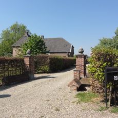 Rossenhof : boerderij met verdieping, hogere middenpartij, schilddak en kroonlijst. Vensters met luiken en zes- en vierruitsramen.