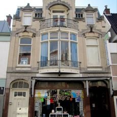 Winkel-woonhuis op rechthoekige plattegrond in overgangsarchitectuur met zowel historiserende als aan de Weense Sezession ontleende motieven. Het winkel-woonhuis is opgenomen in een gesloten gevelrij