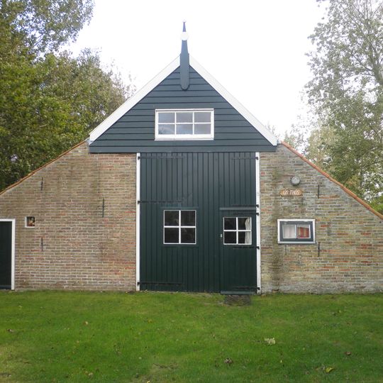 Eenvoudig huisje in de vorm van een boerderijtje aan de voet van de molen