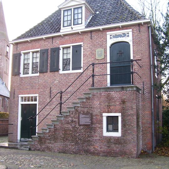 Voormalig raadhuis. Gebouwtje met schilddak. De verdieping bereikbaar via een buitentrap naar een bordes