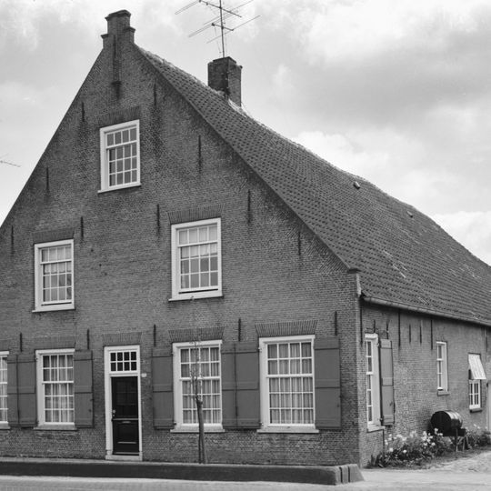Boerderij van het Langstraatse type, met topgevel bekroond door trappen en een pilaster; ramen met kleine roedenverdeling