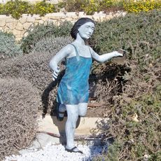 Estatua de una niña corriendo con un libro en la mano. La obra se vincula con el lugar que ocupa por ser este un lugar de inspiración para autores de las letras andaluzas.