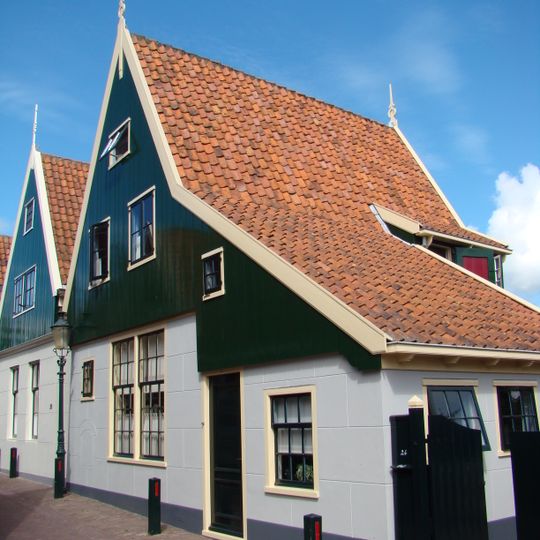 Huis met houten topgevel boven een bakstenen gepleisterde pui
