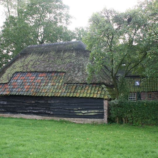 Boerderij onder met riet en pannen gedekt wolfdak. In de voorgevel vensters met luiken en schuiframen met 20- en 25-ruitsroedenverdeling. Deur uit de bouwtijd met eenvoudig bovenlicht