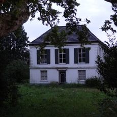 Gepleisterd herenhuis op rechthoekige plattegrond, met geblokte hoeklisenen. Hardstenen cordonlijst tussen souterrain en bel-etage.