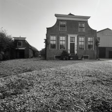 Historisch Museum Hazerswoude: Hoeve met ingezwenkte gevel, waarop houten kroonlijst. Deuromlijsting met hoofdgestel, levensboom, deur uit de bouwtijd.