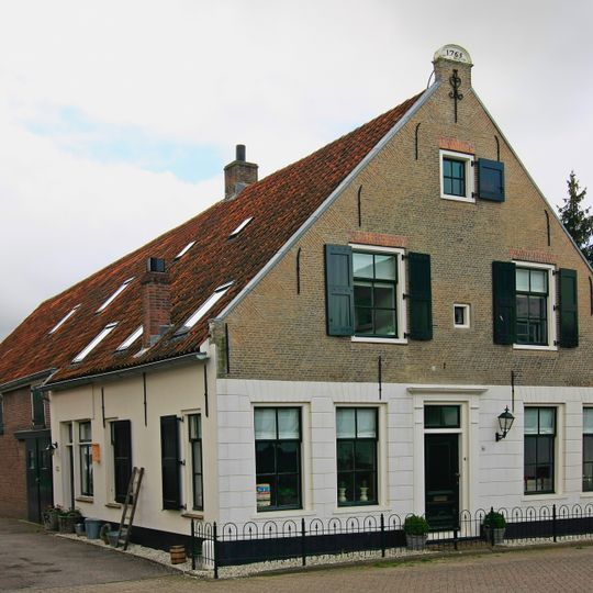 Pand met gepleisterde puntgevel, bekronend fronton en eenvoudige deuromlijsting