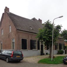 Boerderij, breed woonhuis, rechts onderkelderd, met rieten zadeldak, waarin een dakkapel, waaronder een strolaag