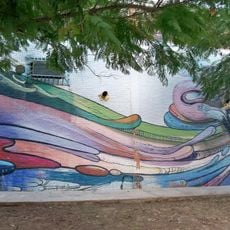 Mural que presenta tres personajes en la parte superior derecha siendo rodeados por lenguas de color.