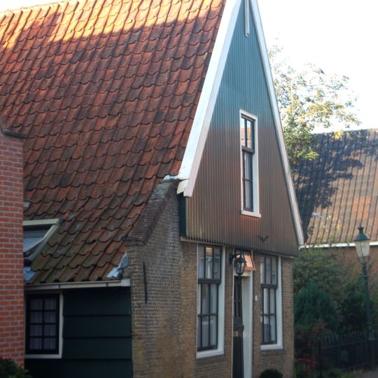 Huis uit hout en steen zonder verdieping met hoog zadeldak