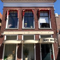 Pand met rechte kroonlijst en etalage in pui onder schilddak met originele frontschoorsteen