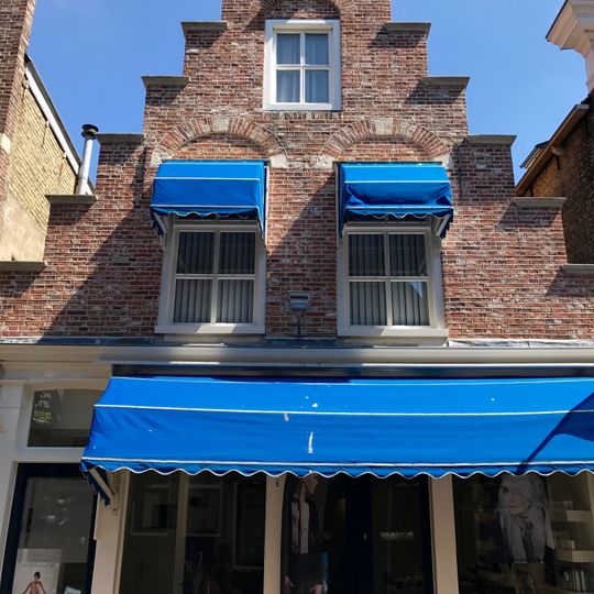 Pand onder zadeldak tussen topgevel achter en gepleisterde trapgevel met verdiepte vensternissen voor