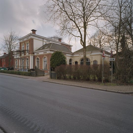 Voorm. dienstwoning met blokbepleistering onder schilddak met sierelementen op de hoeken