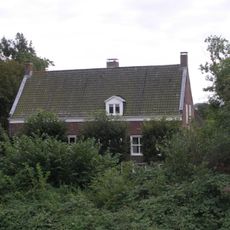 Boerderij op T-vormige plattegrond, waarvan het woongedeelte een zadeldak tussen puntgevels bezit en rechts een opkamer. Vensters met luiken en zes- en vierruitsschuiframen