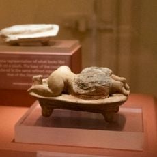 Statuette of a human figure lying face down on bed