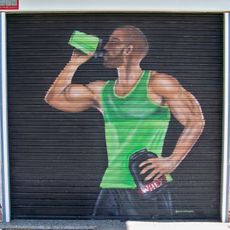 Mural que representa sobre fondo negro a un deportista de medio cuerpo y de perfil bebiendo de un bidón, con camiseta de tirantes verde y pantalón negro.