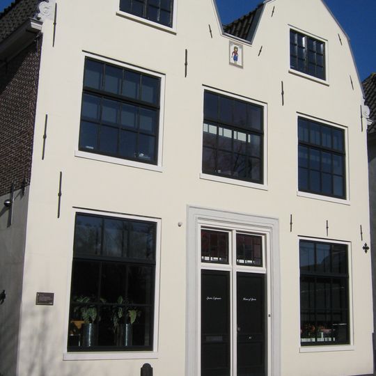 Pand met gepleisterde gekoppelde topgevels met in midden gevelsteen "de korendrager", in 19e eeuw topgevels gewijzigd