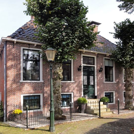 Onderkelderd woonhuis met ingang in het midden en zesruitsvensters onder schilddak met hoekschoorstenen