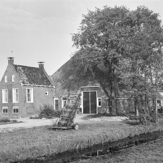 Kop-rompboerderij met onderkelderd voorhuis met zesruitsvensters tussen topgevels met topschoorstenen waarop borden
