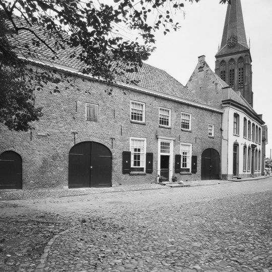 Breed huis onder schilddak. Het gerestaureerde pand heeft een gotische puntgevel met tweelichtskozijnen. Inrijpoort