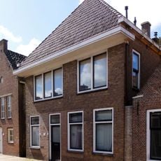 Pand met verdieping met zesruitsvensters en met gootlijst op houten consoles onder met pannen gedekt schilddak