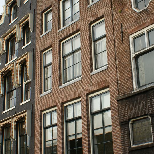 Huis en gevel waarop een van elders overgebrachte hals met schelpblazende zeegodjes aan de vleugelstukken