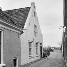 Pand onder zadeldak tegen puntgevel met vlechtingen langs de zijden en aanzettreden