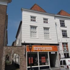 Huis met hoog schilddak en gebosseerd gepleisterde lijstgevel, beganegronds, verbouwd. Op de hoek van de Lombertstraat