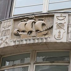 Stone carving above the entrance showing a sailing ship flanked by tools of various trades- .